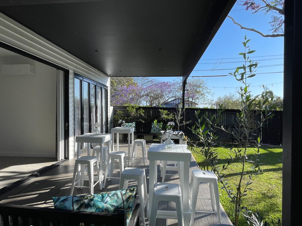 White bar tables and stools arranged for a large covered event