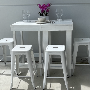 White timber high table and stools styled with orchids and glassware
