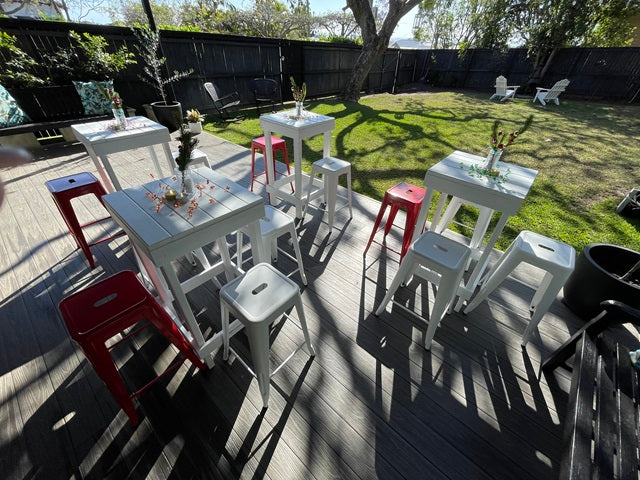 White bar tables and red stools styled for an outdoor celebration