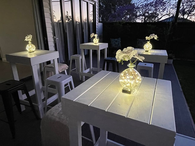 White bar tables with glowing centrepieces at an evening party