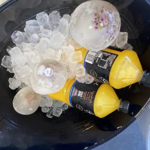 Black party tub filled with ice, decorative ice sphere and chilled drinks