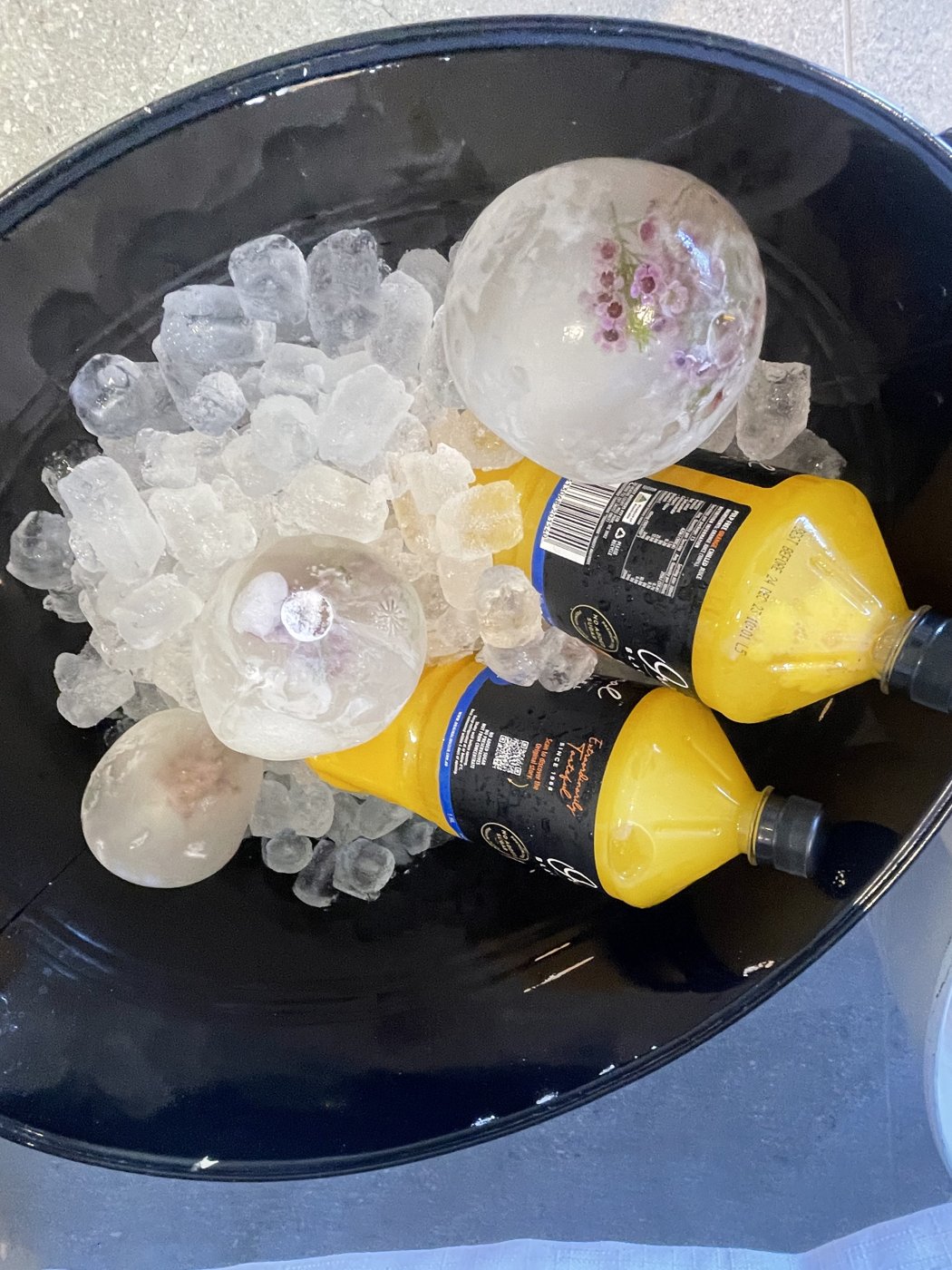 Black party tub filled with ice, decorative ice sphere and chilled drinks