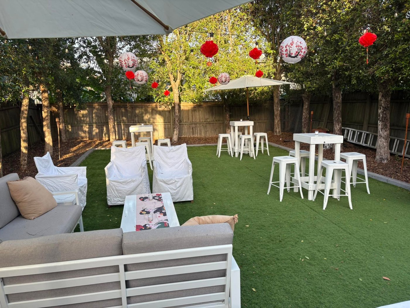 Garden party styled with red paper lanterns, white bar tables and lounges