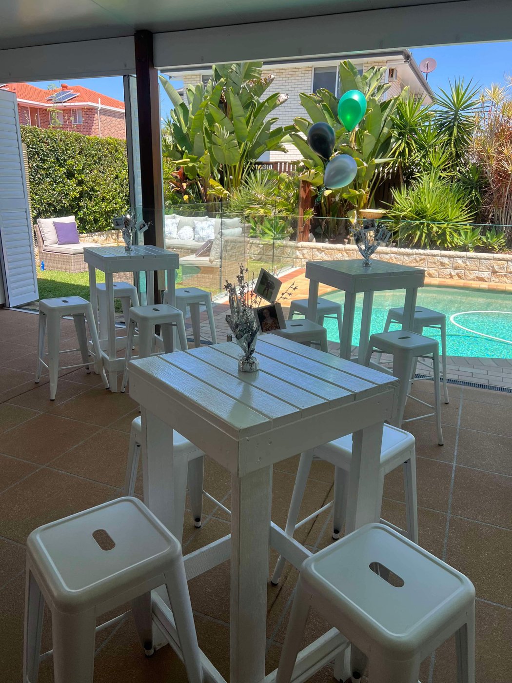Poolside party with white bar tables, stools and balloons