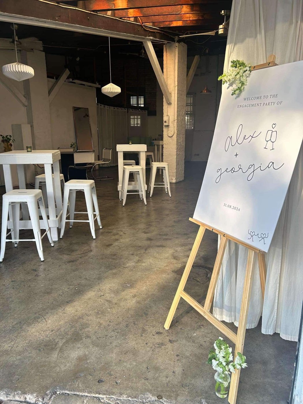 Warehouse event styled with white bar tables and an engagement welcome sign
