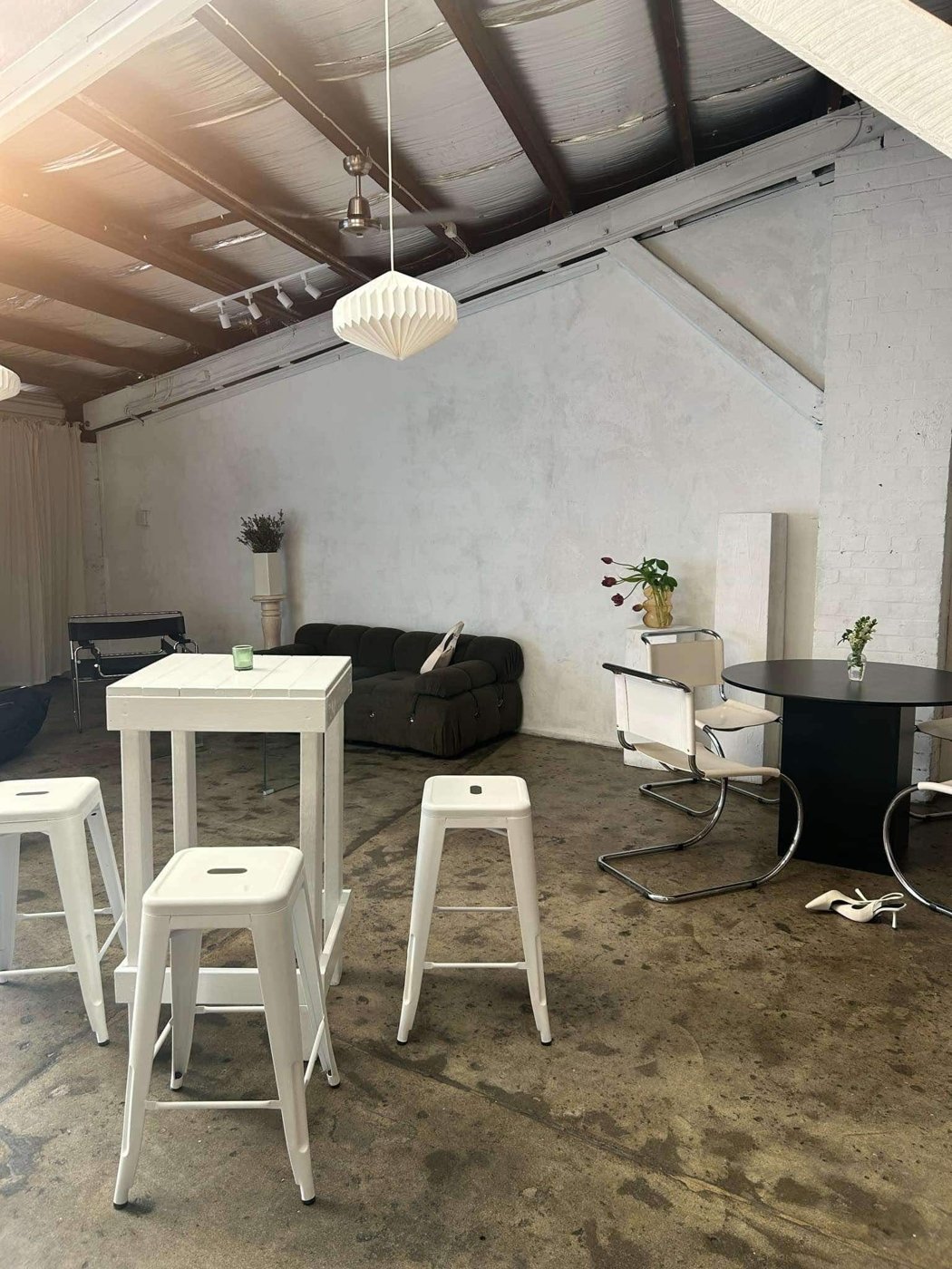 Bright warehouse space with white bar tables, stools and a lounge